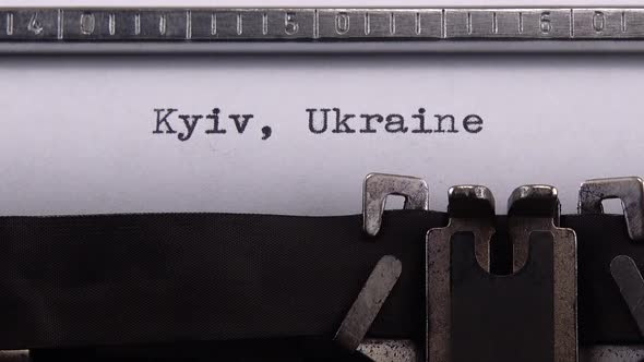 Typing name of Ukrainian city and capital of Ukraine "Kyiv, Ukraine" on retro typewriter.