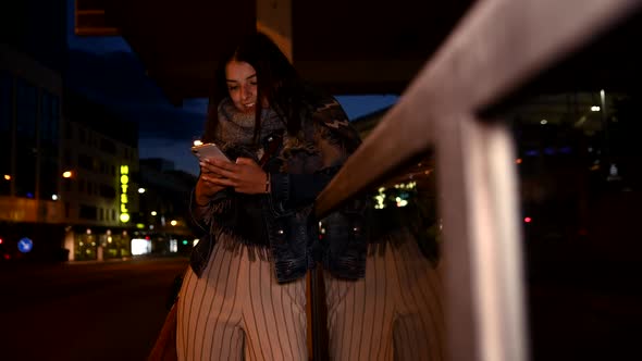 Happy young woman using smartphone at night