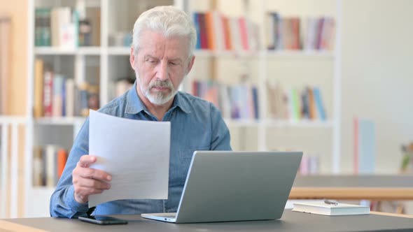 Old Man Working on Laptop and Document