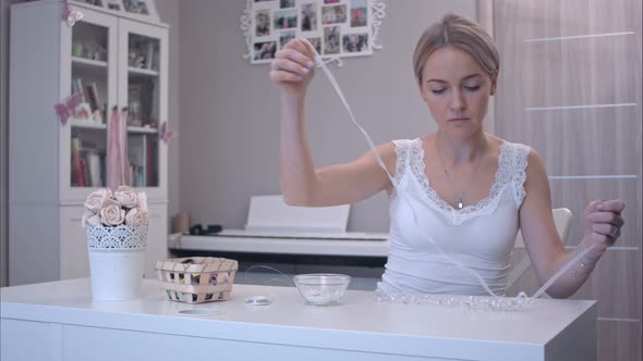 Young Woman Attaching Ribbon To Handmade Jewelry