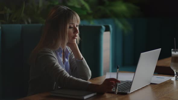 An Asian Woman Student Writes an Online Lecture on Campus with a Pen