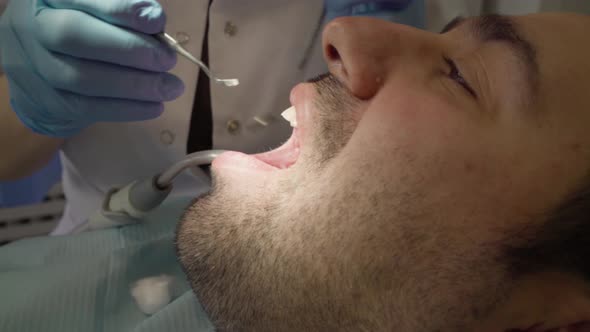 A male patient is having his tooth filled by a dentis woman.