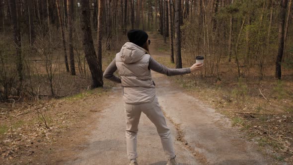 A Woman Make a Fun Dance in  Motion Next To a Pine Forest.