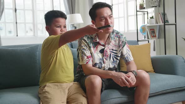 Father And His Son Are Watching Tv While Spending Time Together At Home