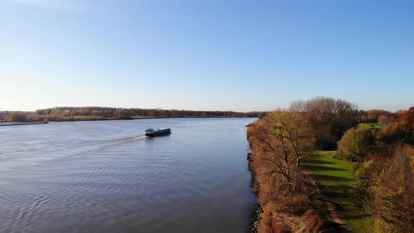 Aerial Rising From Autumnal Path Next To Oude Maas With Ship Going Past In Background