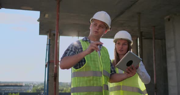 Construction Site Team or Architect and Builder or Worker with Helmets Discuss on a Scaffold