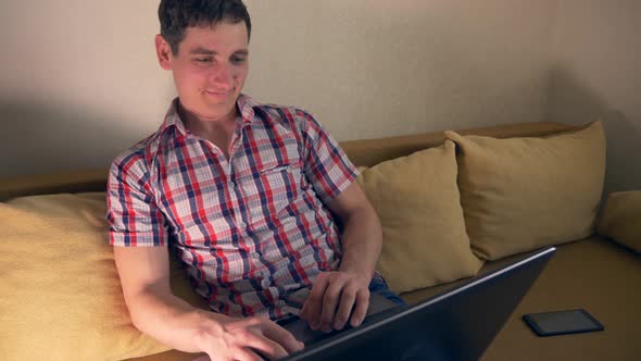 Young Man Using Laptop Surfing Internet Sits On Sofa Couch