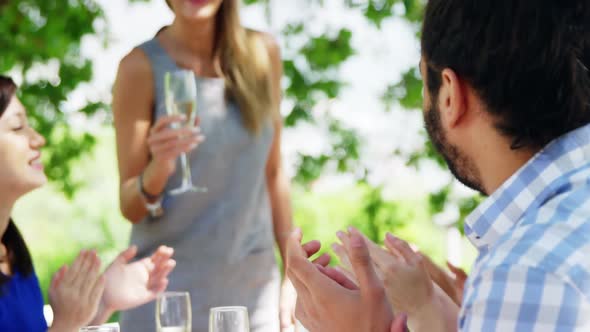 Friends at outdoor lunch applauding for woman