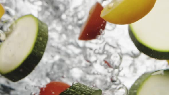 Person Throws Fresh Cut Tomatoes and Zucchini Into Water