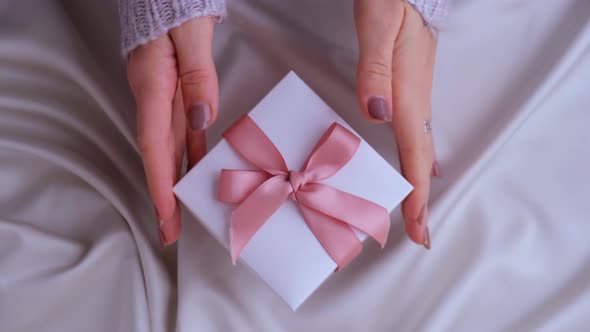 Female Hands Giving and Taking White Gift Box with Pink Ribbon