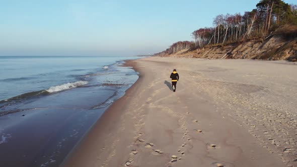 The man in black runs along the beach