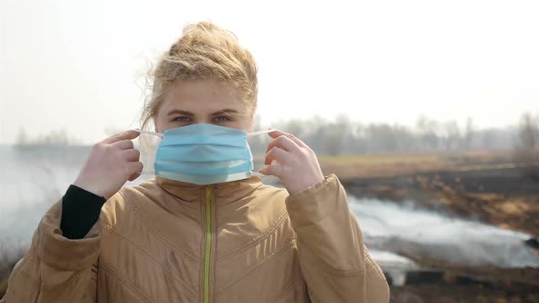 Girl in a Medical Mask Near a Steaming Field