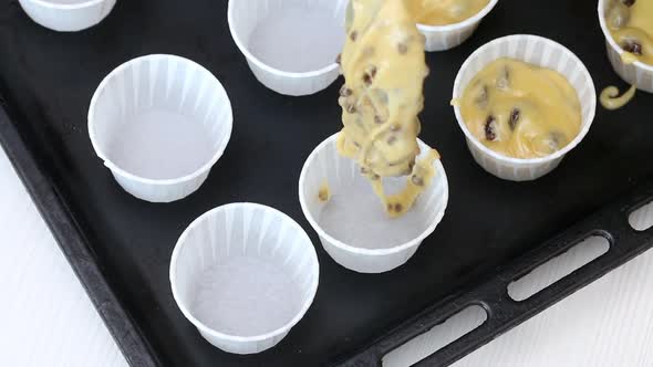 A Woman Puts The Dough Into Muffin Tins On A Baking Sheet.