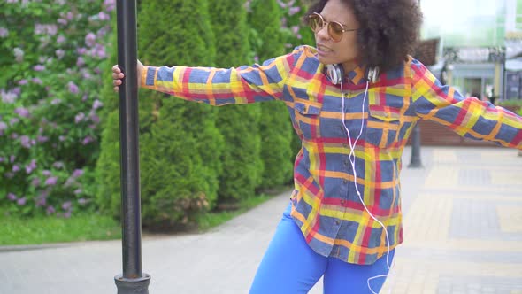 Positive Cheerful African American Young Woman Walking and Dancing on the Streetagainst the Urban