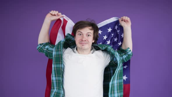 Young Emotional Man Waving American Flag and Shouting on Purple Background