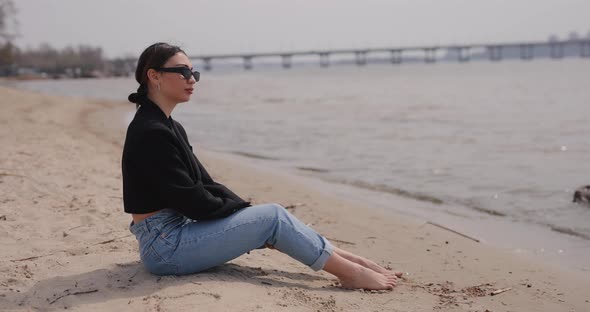 Woman Sitting on the Beach and Relaxes