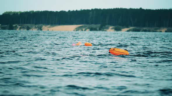 Two Open Water Swimmers Swimming with a Floating Bags in a River