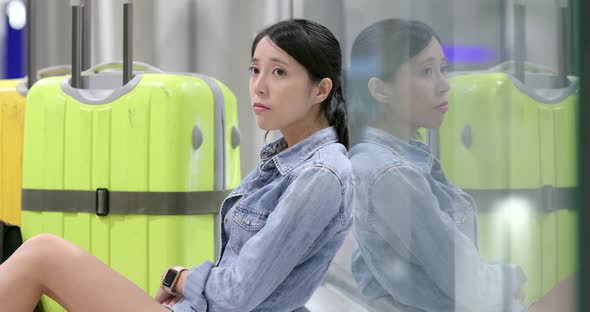 Woman feeling bored and waiting for flight in airport with her luggage and backpack