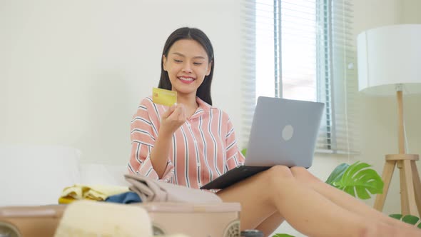 Asian young woman use credit card to pay for booking hotel in bedroom.