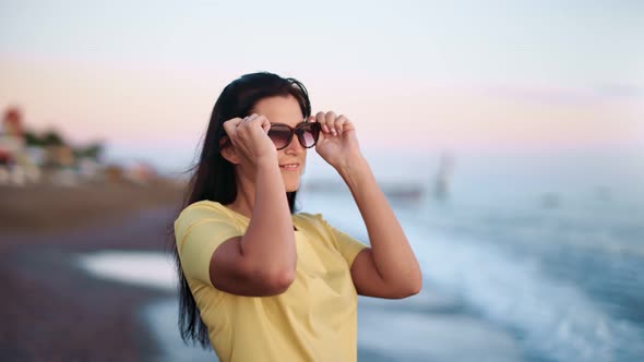 Smiling Woman in Yellow Dress Wearing Sunglasses Admiring Seascape