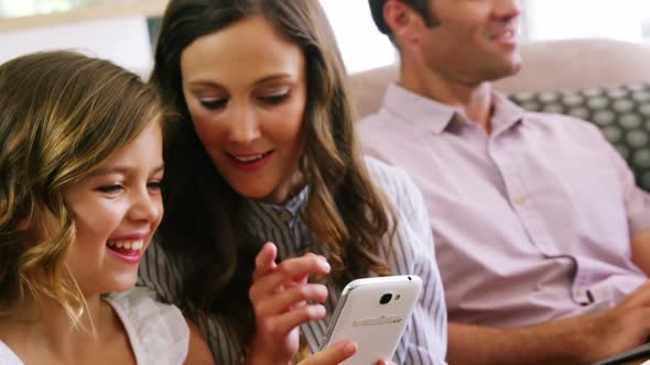 Mother and daughter using mobile phone in living room