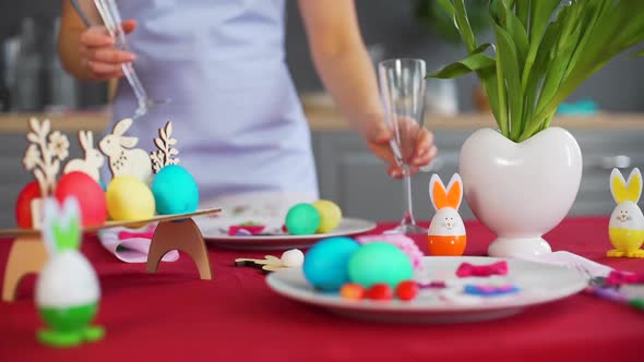 Young Woman Putting Wineglasses on Easter Table