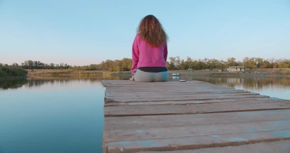 Portrait of a Woman Sitting on a Wooden Pier, Looking at the Lake Feels Free. Concept Freedom