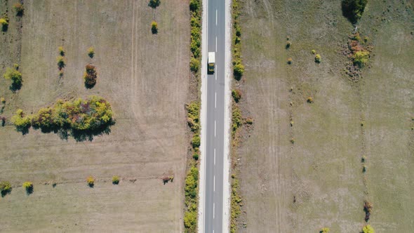 Top Aerial View of an Empty Asphalt Road on the Plateau Between Green Fields