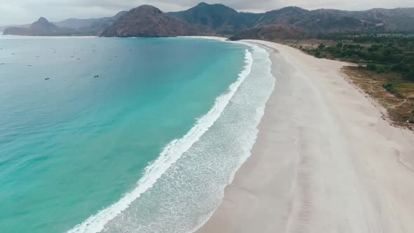 Aerial view waves break on white sand beach