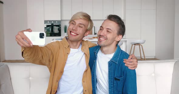 Homosexual Couple Hugging Looking at Smartphone Camera When Making Selfie Photos