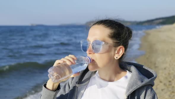 Girl Drinks the Purest Water of Lake Baikal Standing on the Baikal Shore