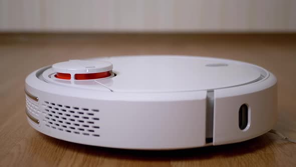 A Modern Automatic Robot Vacuum Cleaner Sweeps the Floor in Room