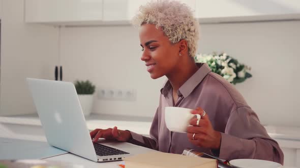 Young African American Woman Looks Series at Laptop Screen Breakfast Smiles