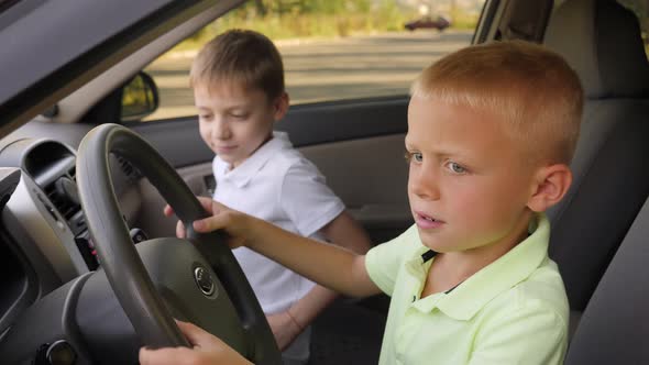 A Little Boy and His Brother Sitting in the Car Behind the Wheel and Playing