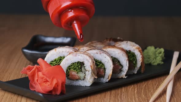 Appetizing Sushi is Poured with Sweet Sauce on a Wooden Table in Restaurant