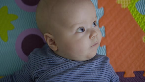 Close Cute Newborn Lying on Carpet Looking and Blinking His Eye Into Camera