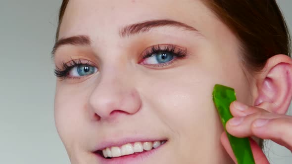 Young Woman Holds Leaf of Aloe Vera