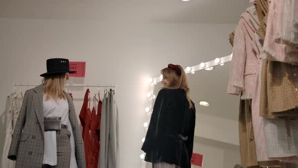 Stylish Blonde Female with Friend Trying on Clothes in Store