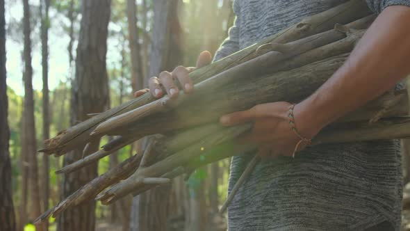 Mid section of man with wooden sticks walking in the forest 4k