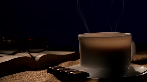 Coffee Cup with Book, Glasses and Bar of Chocolate, on Black Background
