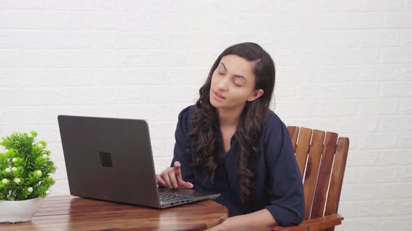 Tired Indian girl working on a laptop