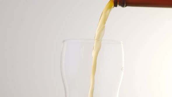 Pouring Beer Into a Glass From a Bottle on a White Background