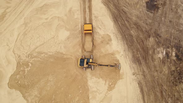 Excavator Loading Sand Into a Truck Body in Sand Quarry