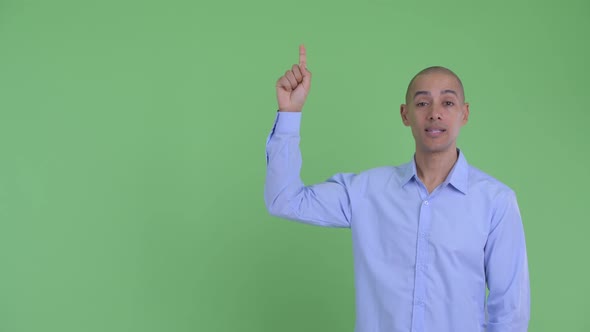 Happy Bald Multi Ethnic Businessman Talking While Pointing Up