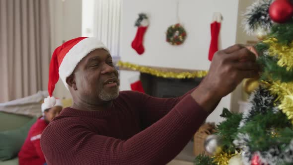 Happy senior african american couple decorating christmas tree in the living room