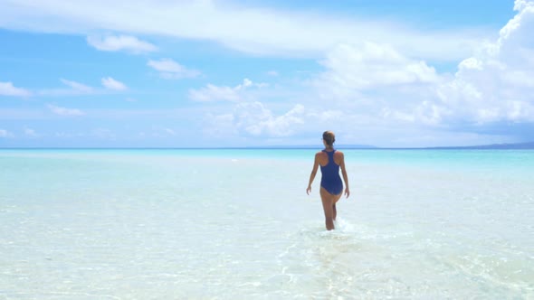 Woman sunbathing walking in turquoise water white sand beach tropical sea