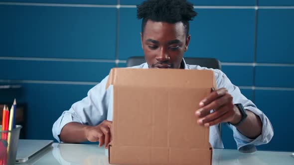 Excited African Man Receives Parcel Open Box at Home Satisfied with Great Goods