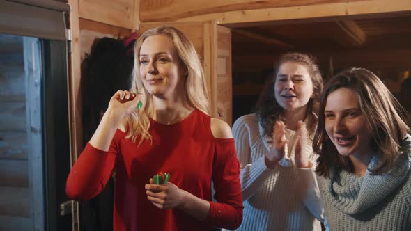 Young Blond Woman Throwing Arrows Into the Target and Friends Cheering