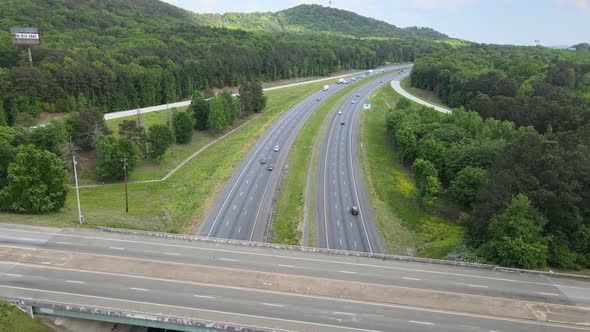 Vehicles driving on the interstate with a curve in the road. An overpass shows vehicles crossing ove