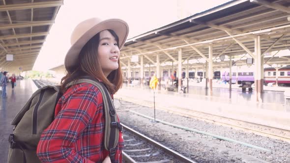 Happy Asian woman waiting the train at train station for travel in summer.